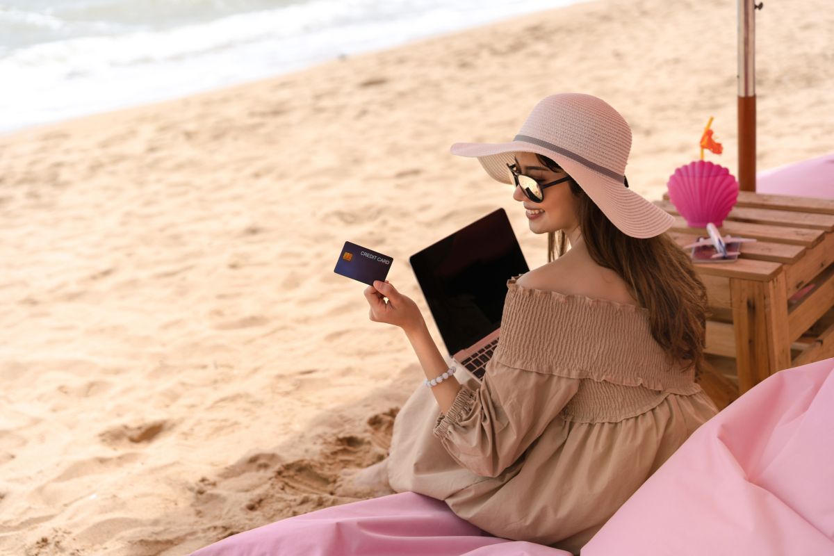 Femme avec une carte bancaire sur la plage.: astuces carte bancaire voyage