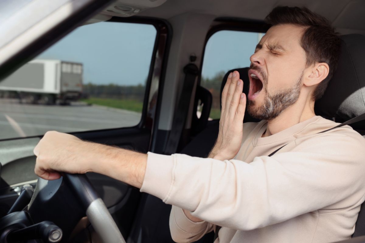 Un homme bâillant en conduisant une voiture.